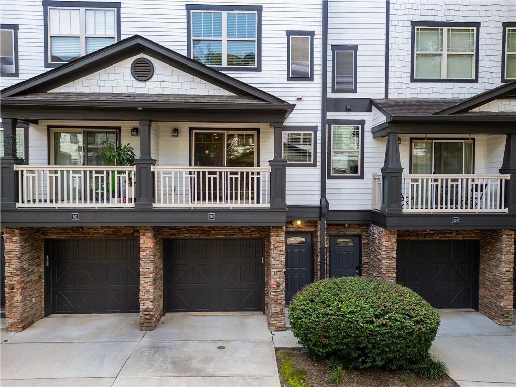 Townhome unit 260 with a covered porch, stone-clad columns, and dark garage doors.