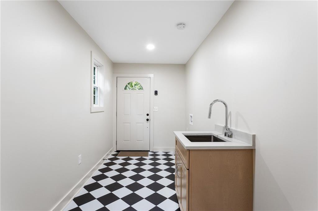 Utility room with a sink cabinet, exterior door, and black-and-white checkerboard floor.