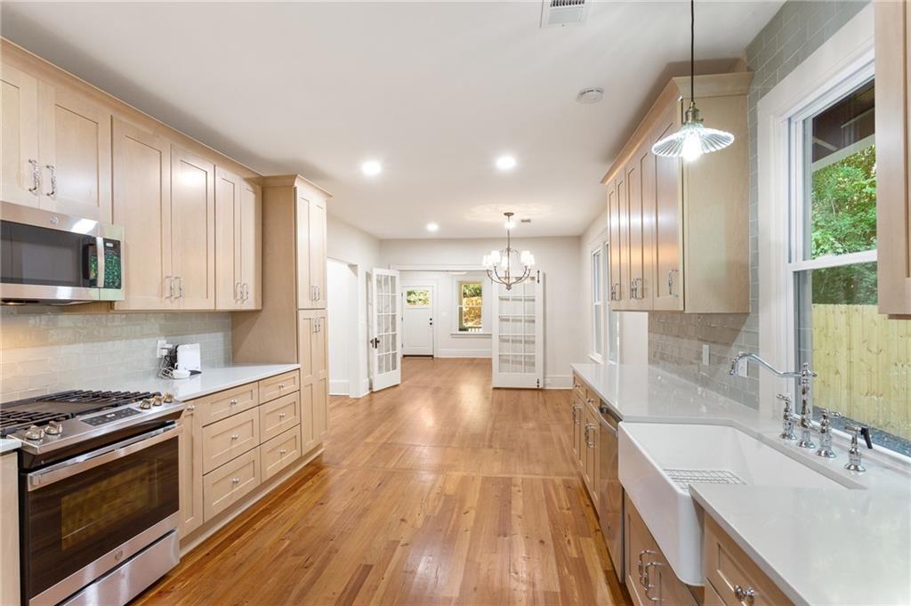 Renovated kitchen with light wood cabinets, a farmhouse sink, and hardwood floors.