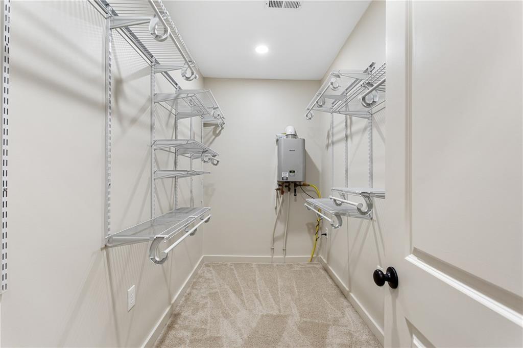 Walk-in closet with extensive wire shelving and a wall-mounted tankless water heater.