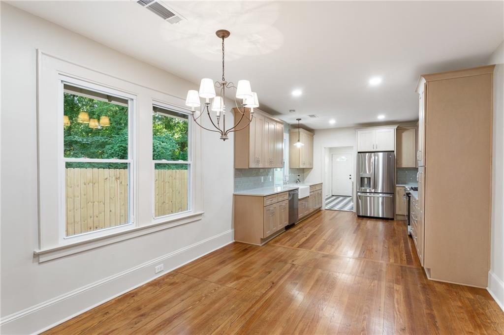 Kitchen with hardwood floors, light wood cabinets, stainless steel appliances, and large windows.