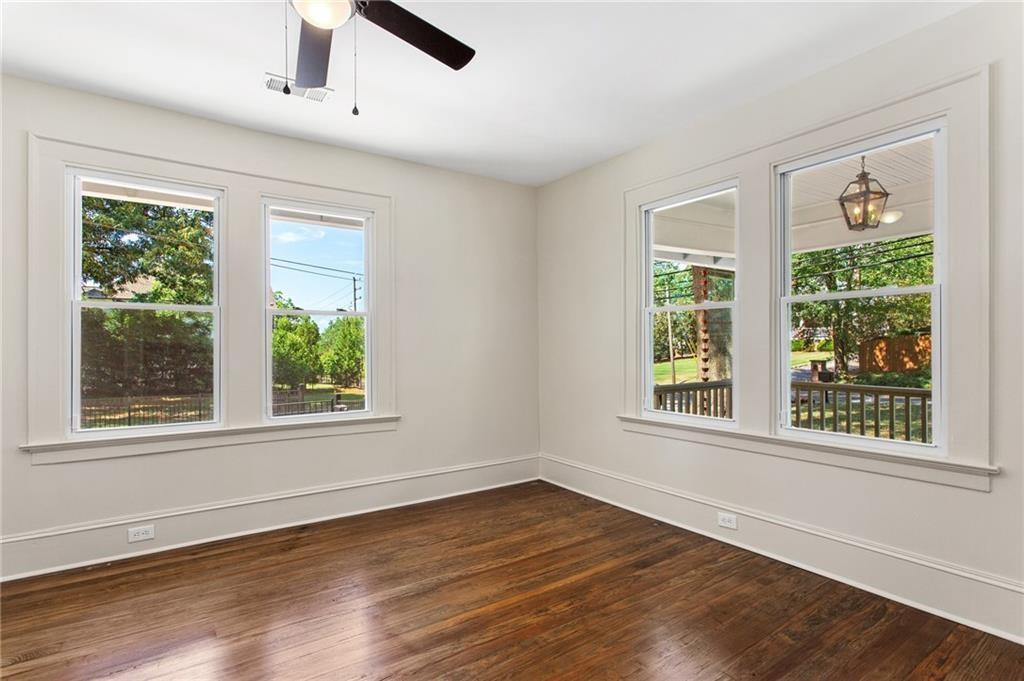 Empty room with hardwood floors, four windows, and a view of the covered porch.