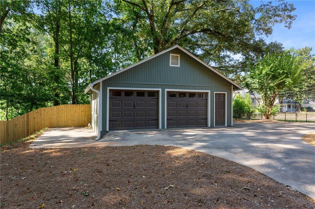 Detached green garage with two dark doors and a separate side entry beneath mature trees.