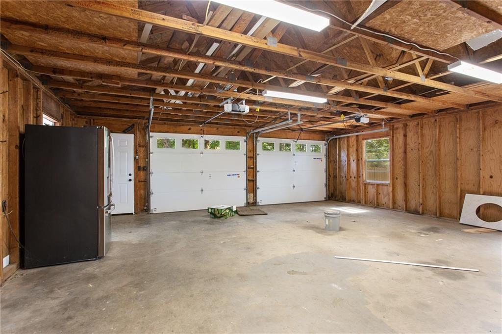 Unfinished two-car garage with exposed wood framing, two overhead doors, and a concrete floor.