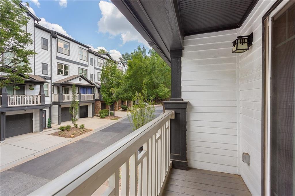 Covered balcony overlooking neighboring townhomes and a tree-lined residential lane.