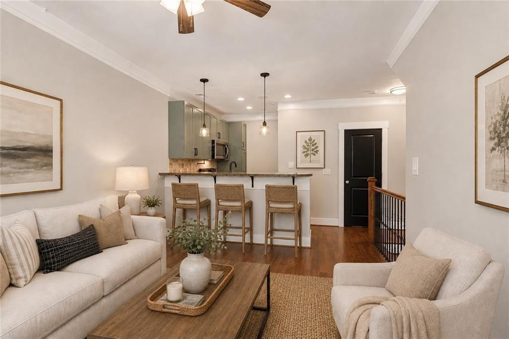 Open-plan living room with a breakfast bar, neutral sofas, and hardwood floors.