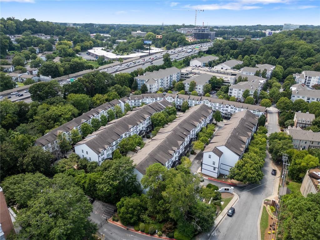 Aerial view of a tree-lined residential complex beside a busy highway.