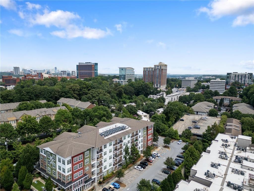 Aerial view of an apartment building, tree-lined neighborhood, and Atlanta skyline.