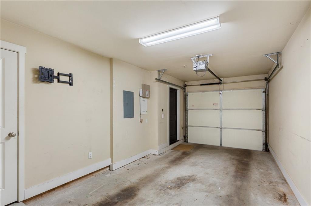 Empty garage with a closed overhead door, concrete floor, and ceiling-mounted opener.