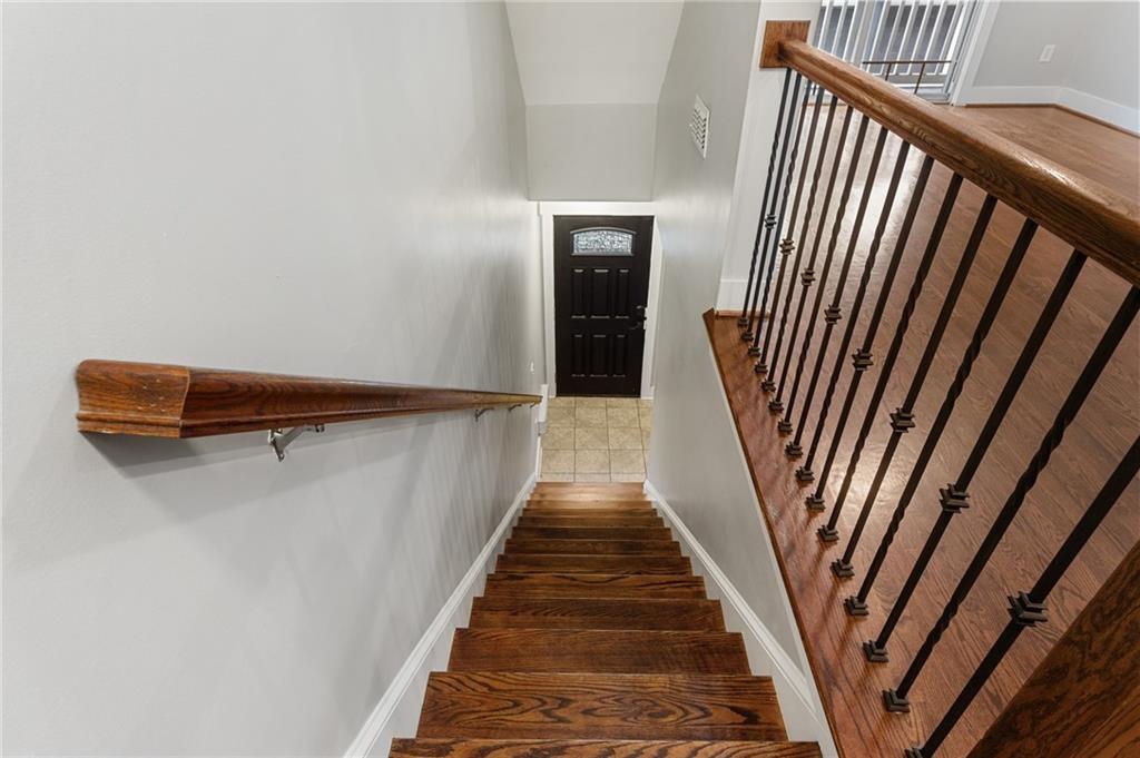 Wooden staircase with dark metal railing leading to a black front door.