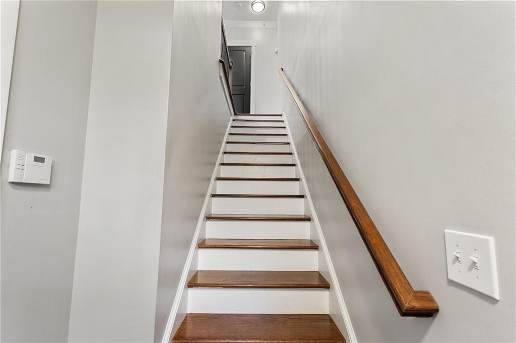 Interior staircase with dark wood treads and handrail leading to a dark door.