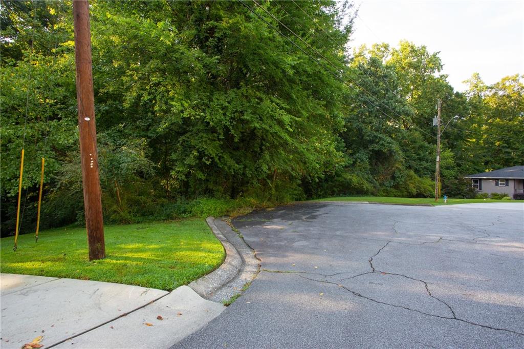 Wooded property frontage beside a curved residential street, with utility poles and overhead lines.