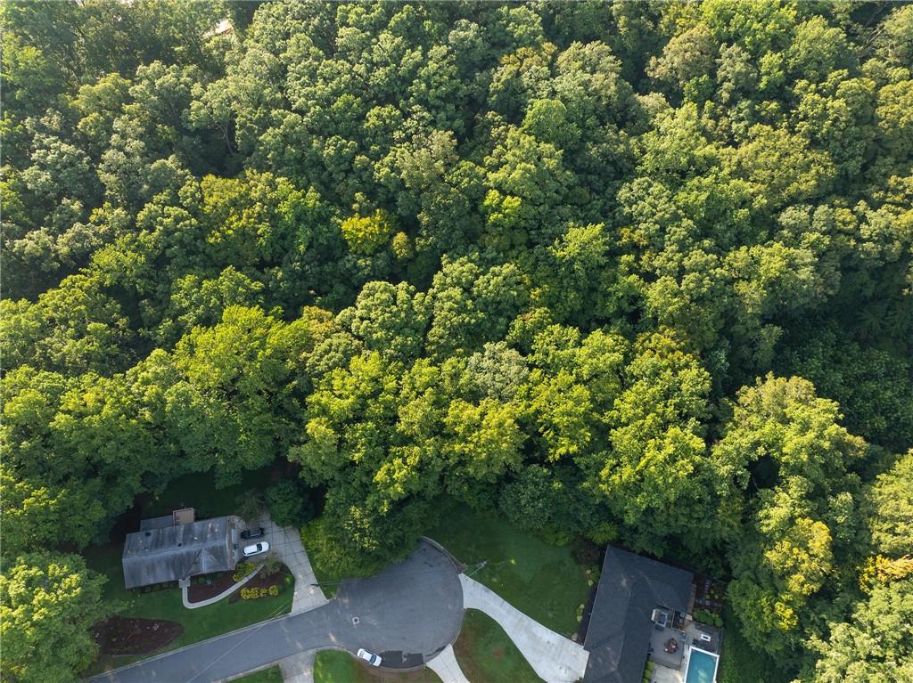 Aerial view of homes on a wooded cul-de-sac, with a swimming pool beside one house.