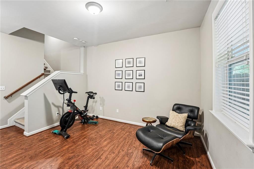 Furnished room with an exercise bike, staircase, and black leather lounge chair beside a large window.