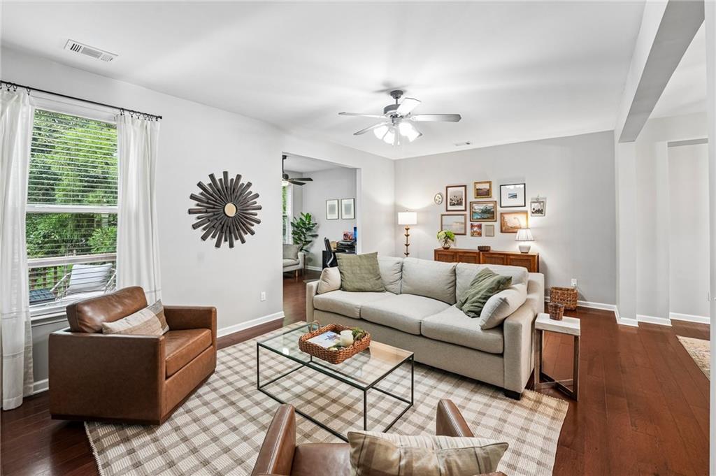 Living room with a gray sofa, leather armchair, plaid rug, and framed wall art.