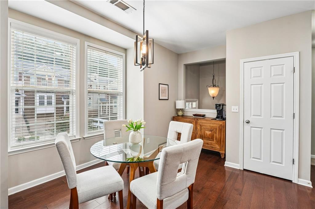 Dining room with a glass-top table, upholstered chairs, and large windows with blinds.