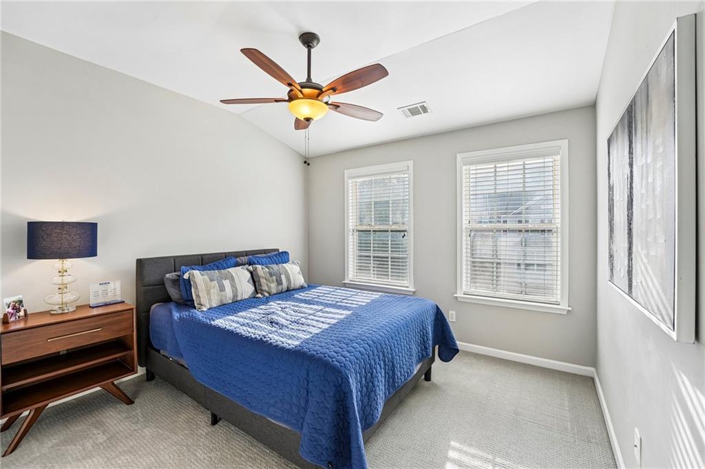 Staged bedroom with a blue bed, two windows, and a wooden nightstand.