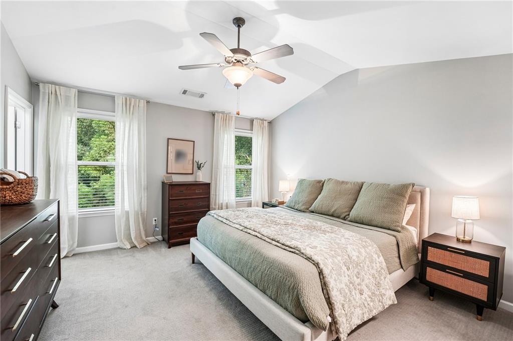 Bedroom with a large bed, pale green bedding, tall windows, and a ceiling fan.