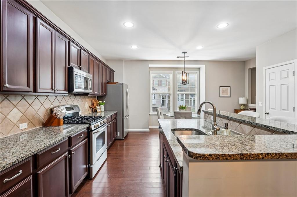 Kitchen with cherry cabinets, granite island, stainless steel appliances, and a dining nook by the windows.