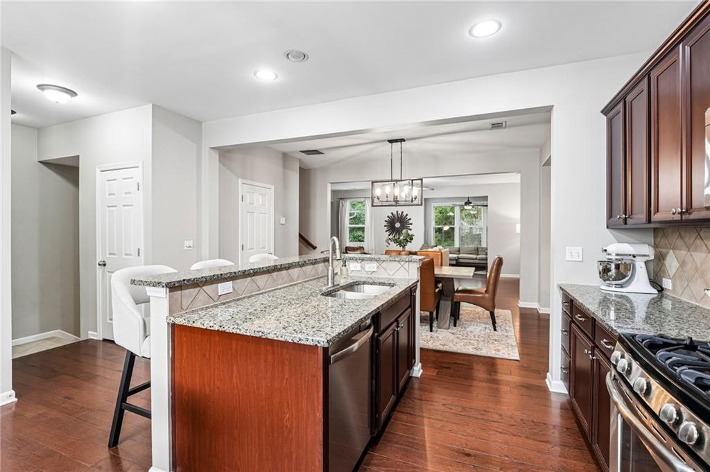 Open-plan kitchen with a granite island, dark wood cabinets, and dining and living areas beyond.