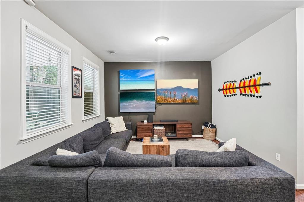 Living room with a large gray sectional, wall-mounted screens, and colorful arrow decor.