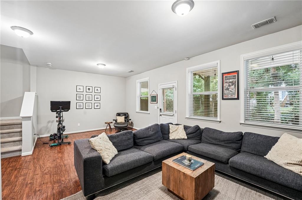 Living room with a charcoal sectional, wood coffee table, and exercise equipment near the windows.