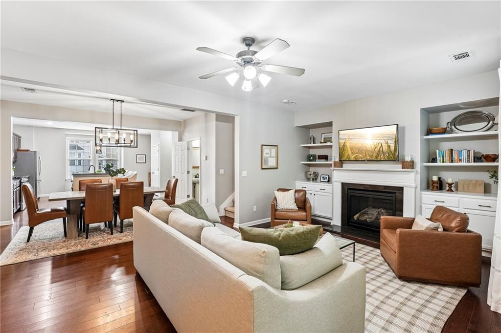 Open-plan living and dining room with a fireplace, built-in shelves, and hardwood floors.
