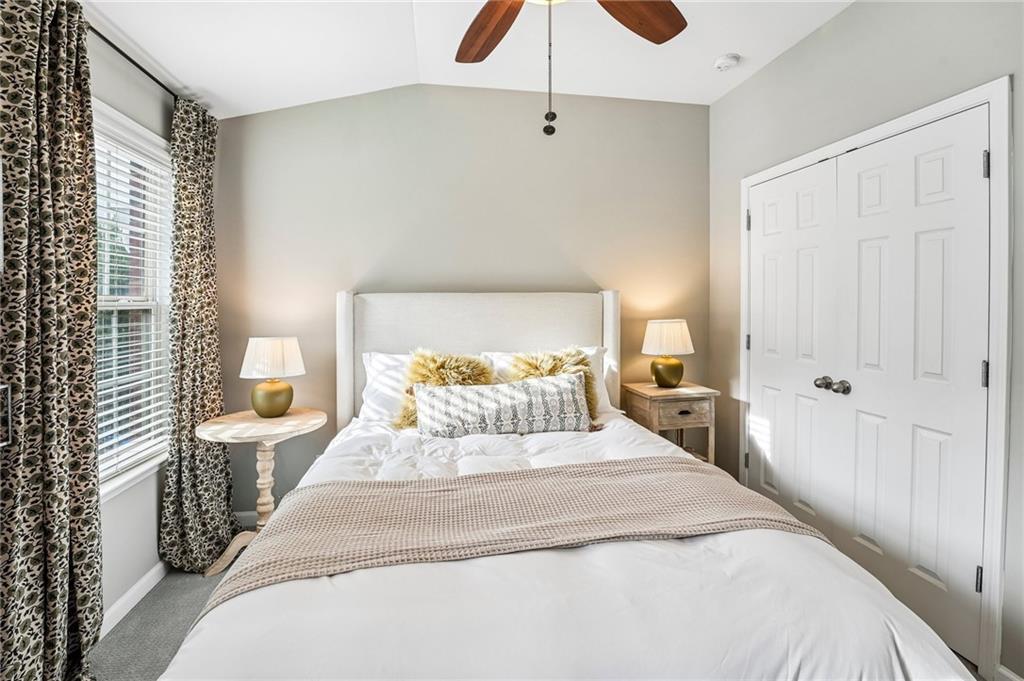 Bedroom with a white upholstered bed, patterned curtains, and white double closet doors.