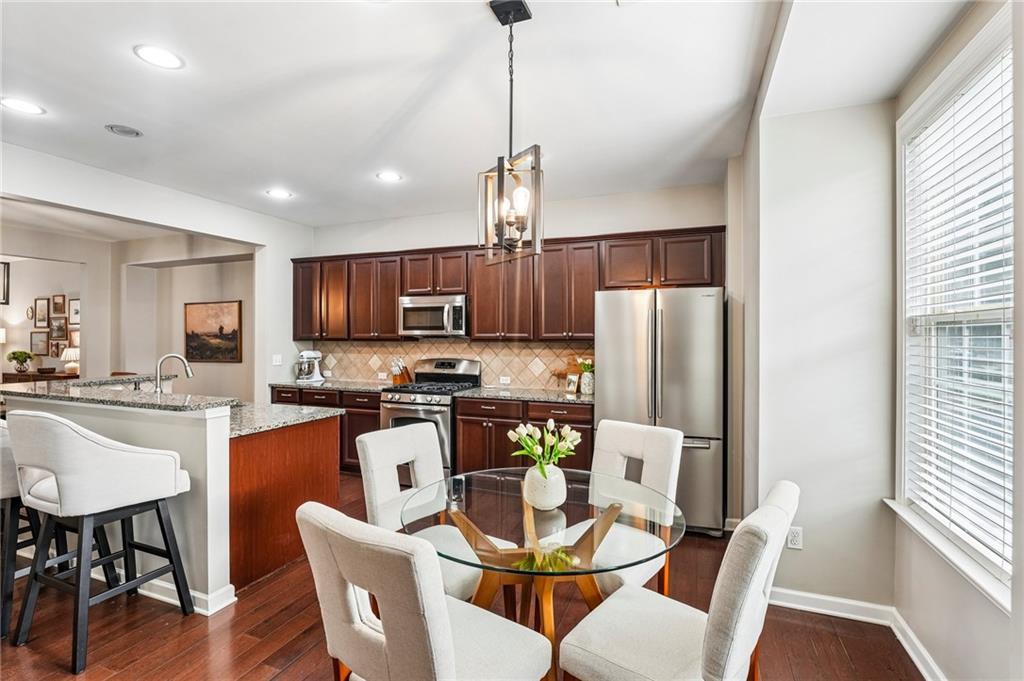 Kitchen and dining area with cherry cabinets, stainless steel appliances, and a glass table by a large window.