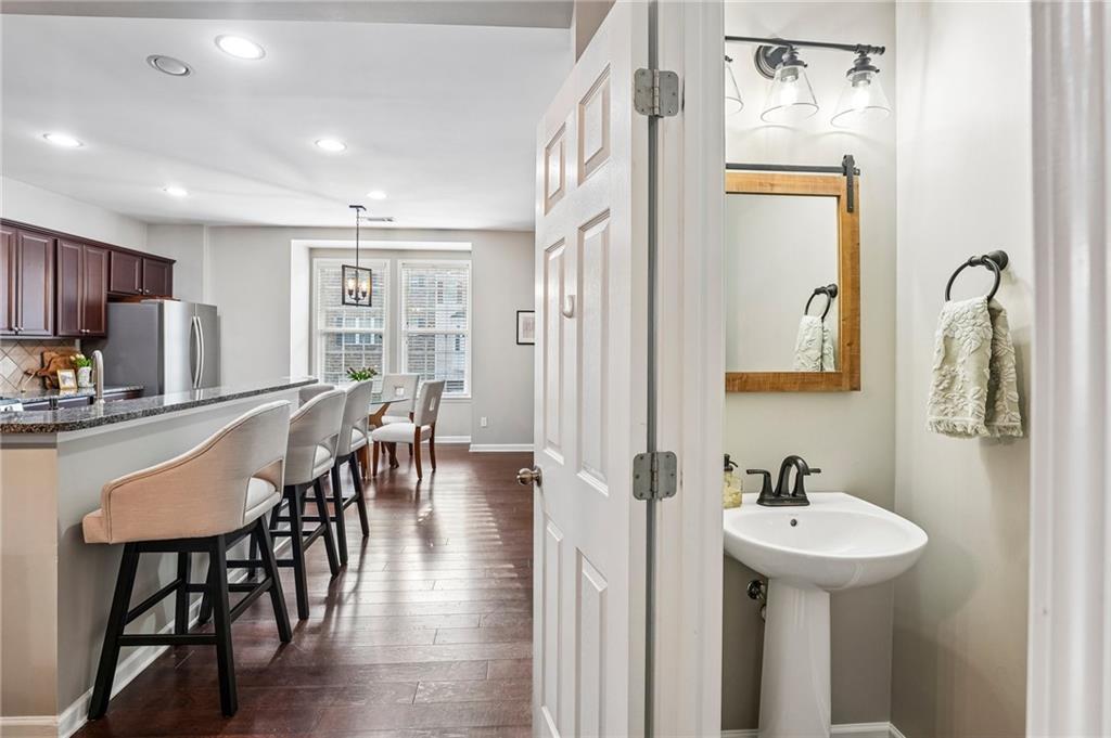 Kitchen and dining area with dark wood floors, breakfast bar, and adjacent powder room.