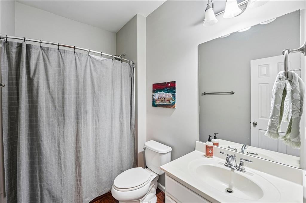 Bathroom with a gray shower curtain, white toilet, and vanity with an oval sink and large mirror.