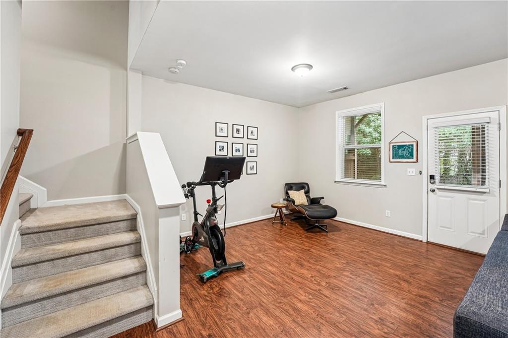 Recreation room with an exercise bike, lounge chair, and carpeted staircase.