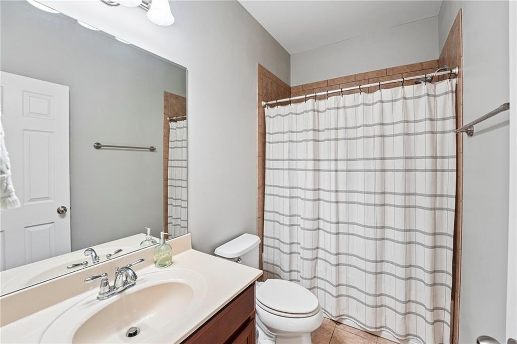 Bathroom with a dark wood vanity, large mirror, and striped shower curtain.
