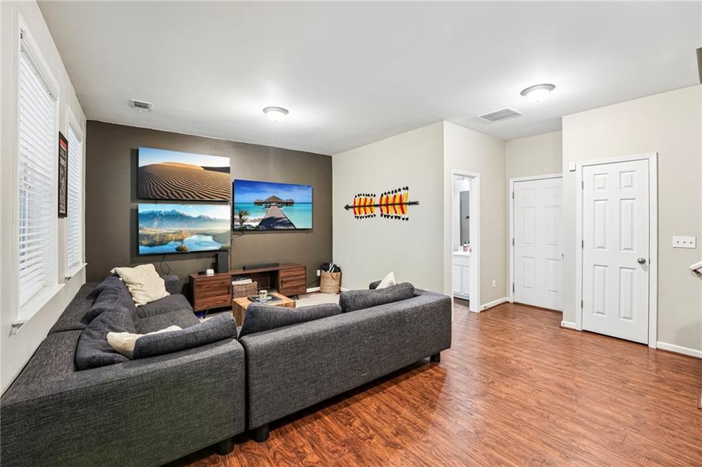 Living room with a gray sectional, landscape prints, and warm wood flooring.