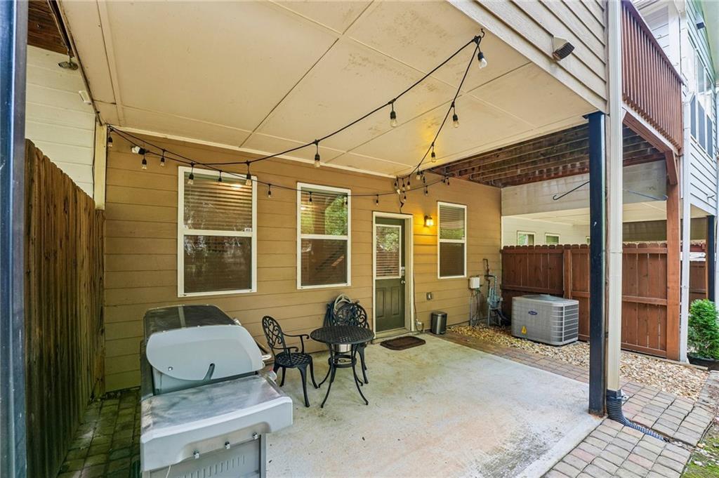 Covered patio with string lights, outdoor seating, grill, and fenced courtyard.