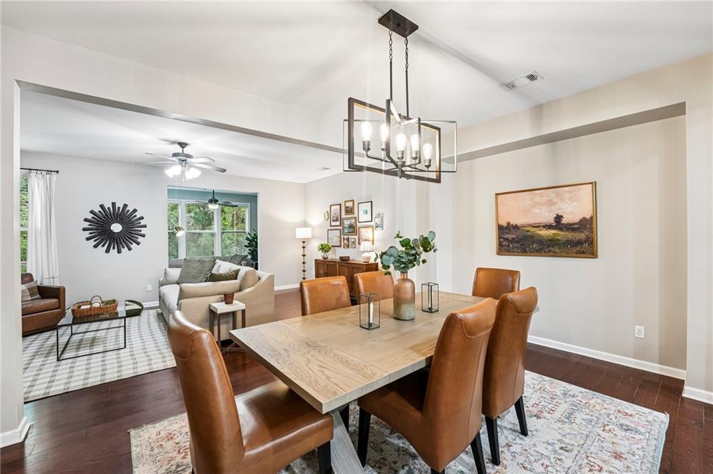 Dining room with a wood table and leather chairs, open to a bright living room.