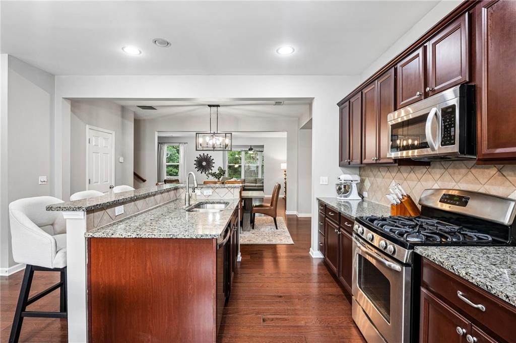 Kitchen with cherry cabinets, granite island, stainless steel appliances, and gas range.