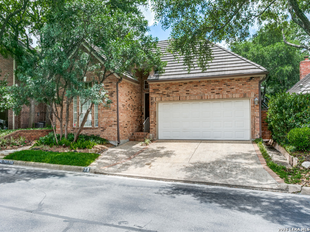 Brick one-story garden home at 79 Longsford with a two-car garage and shaded front landscaping.
