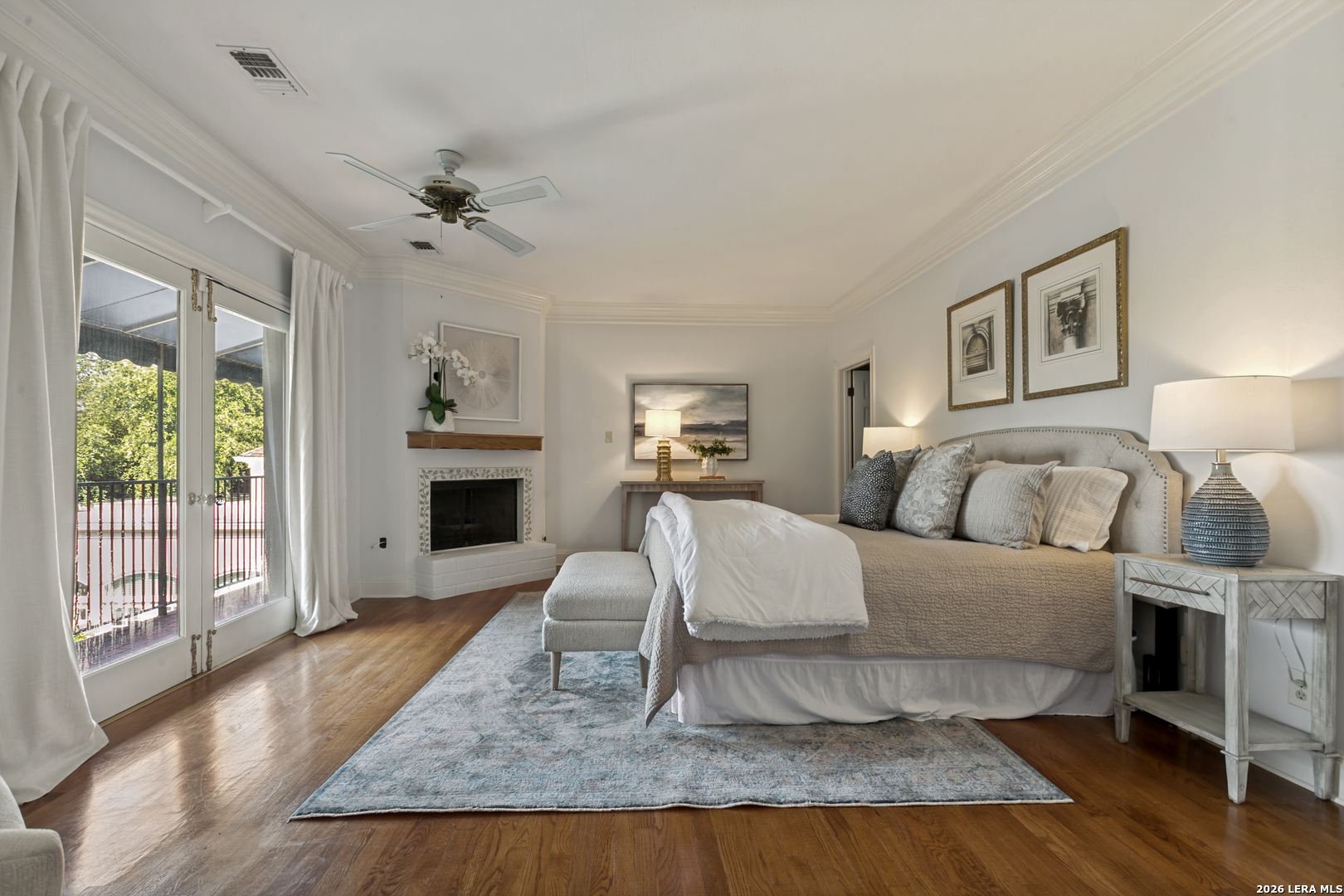 Terrell Hills primary suite with a fireplace, private balcony access, and abundant natural light.