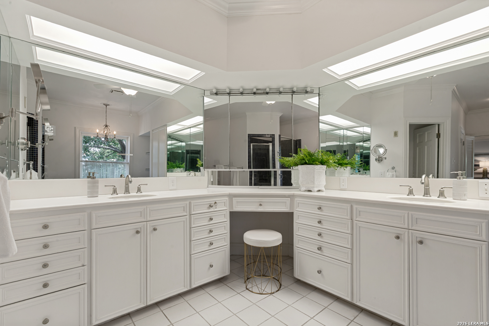 Bright primary bathroom in a Terrell Hills home with dual vanities, skylights, and a dedicated vanity area.