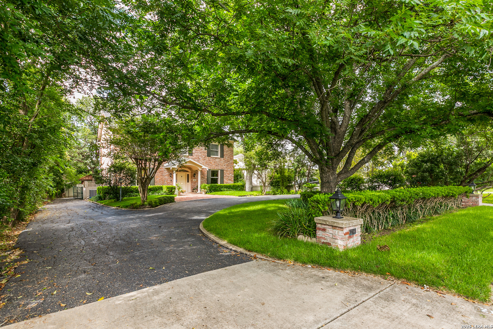 Terrell Hills home with a circular driveway, mature oak trees, and established landscaping on a spacious lot.