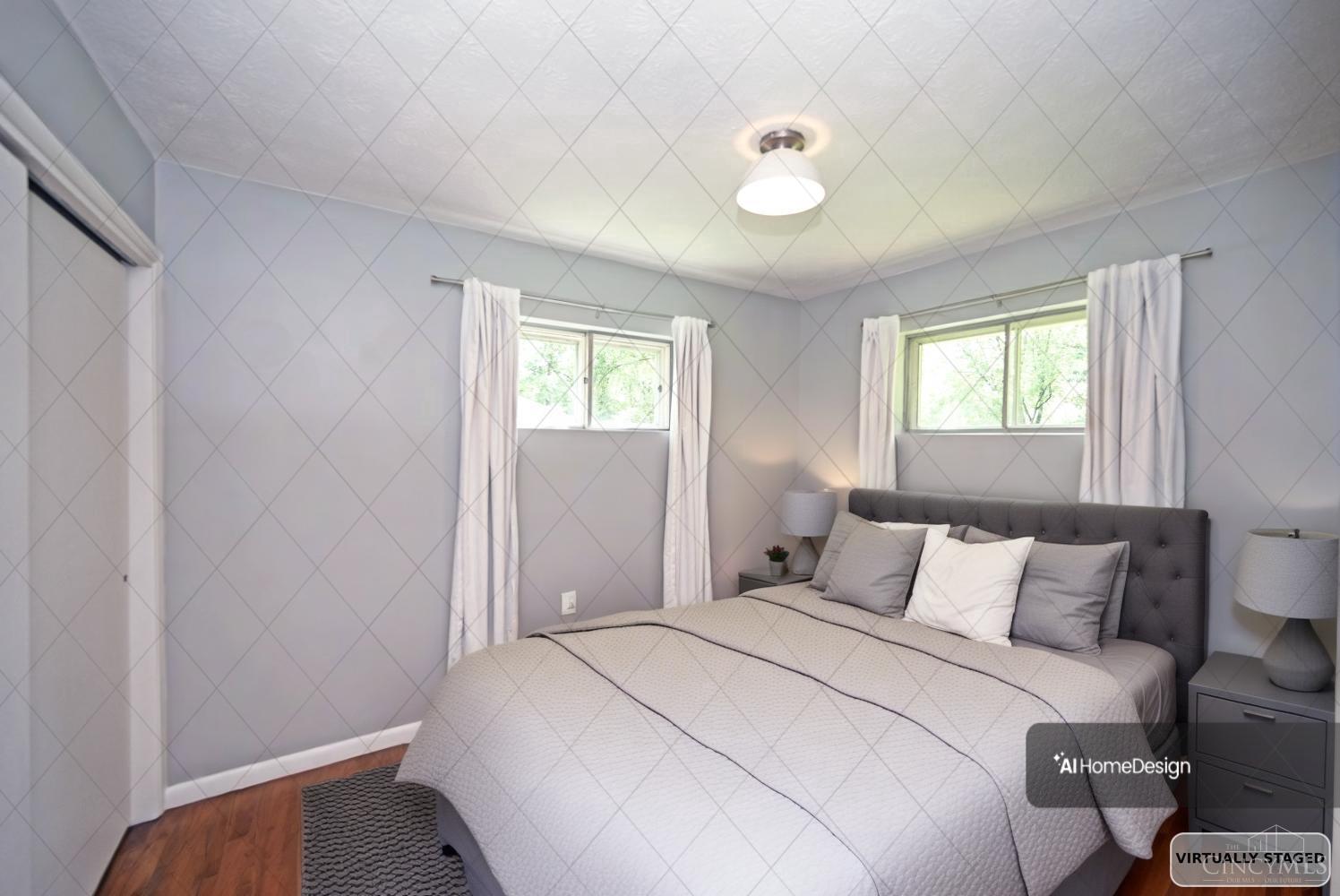 Virtually staged bedroom with a gray tufted bed and two curtained windows.