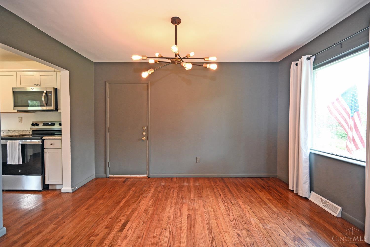 Dining area with hardwood floors, a modern ceiling light, and a window overlooking an American flag.