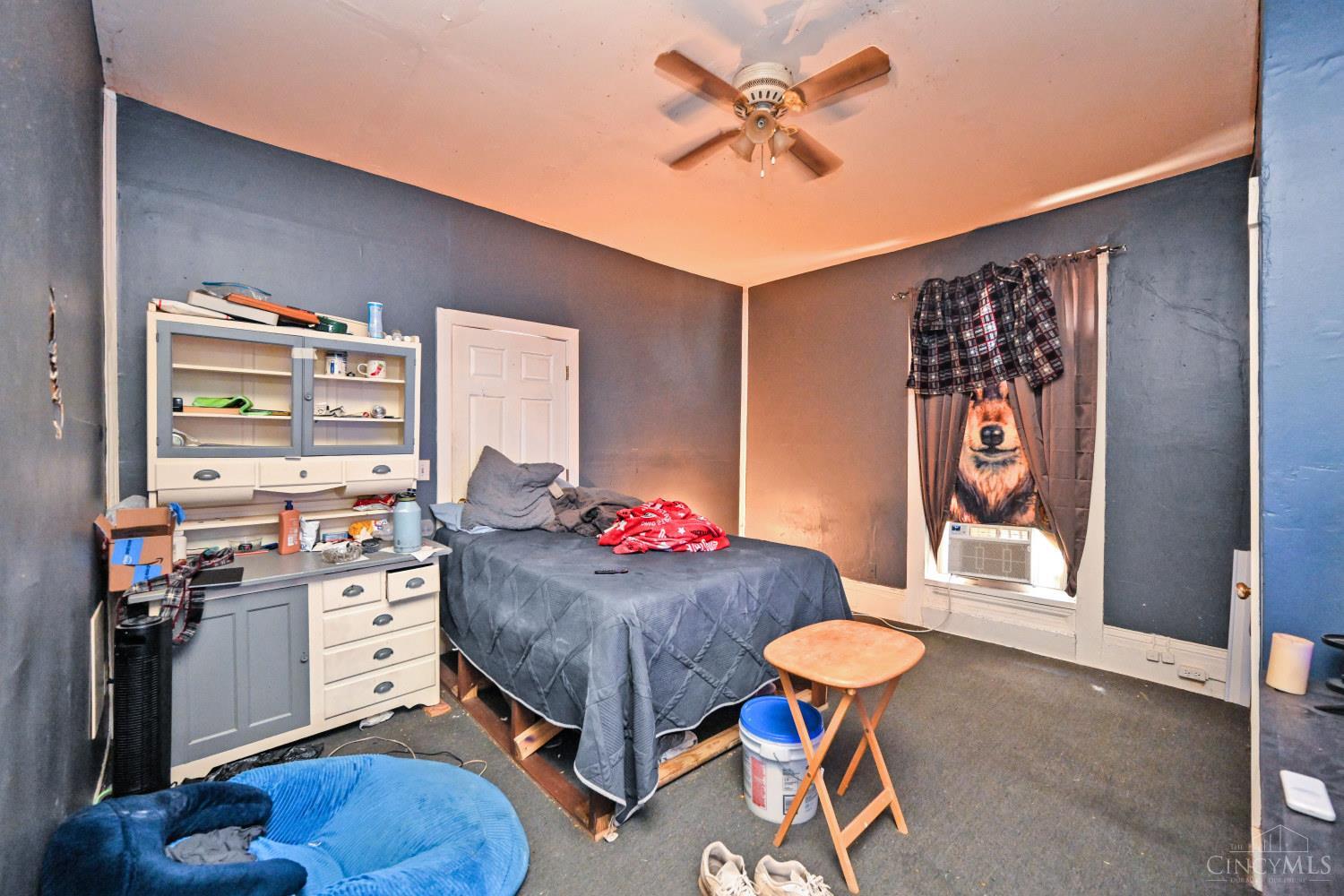 Bedroom with dark blue walls, a bed, a large hutch, and a window air conditioner.