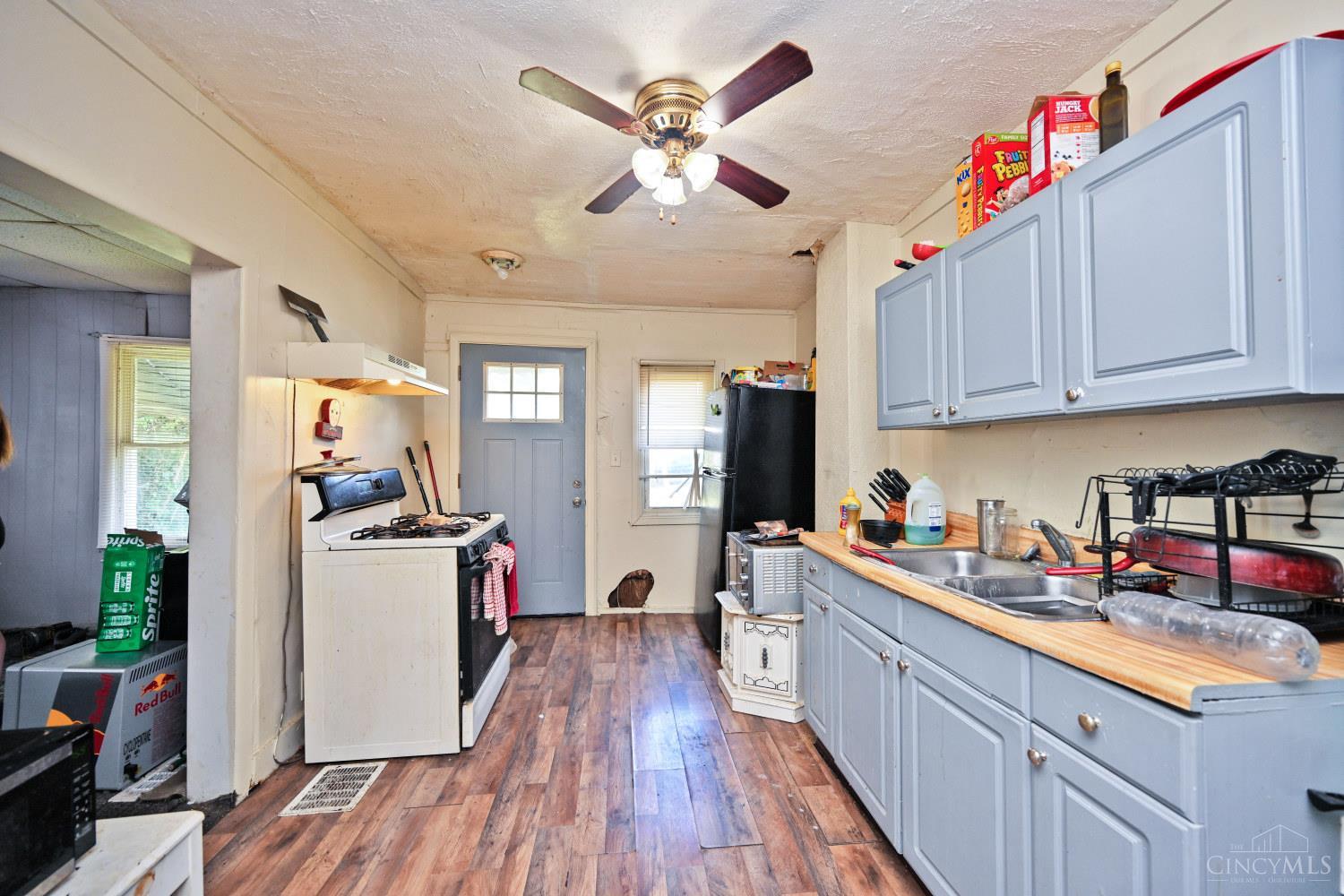 Kitchen with pale blue cabinets, wood countertops, a gas stove, and a ceiling fan.