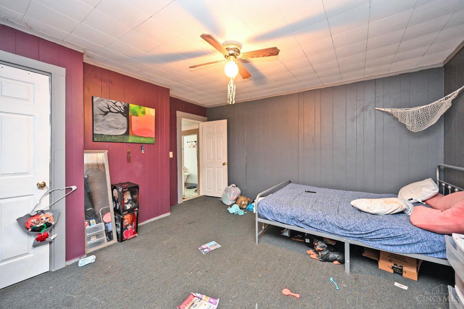 Bedroom with gray paneled walls, a burgundy accent wall, and a metal bed.