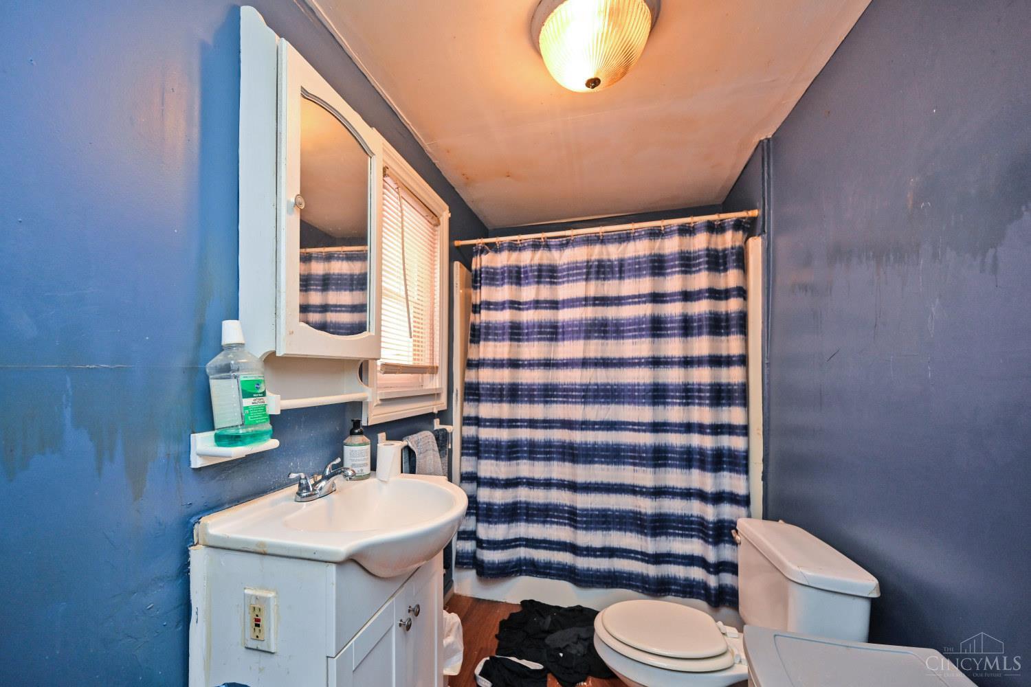 Bathroom with blue walls, a white sink and toilet, and a blue-and-white striped shower curtain.