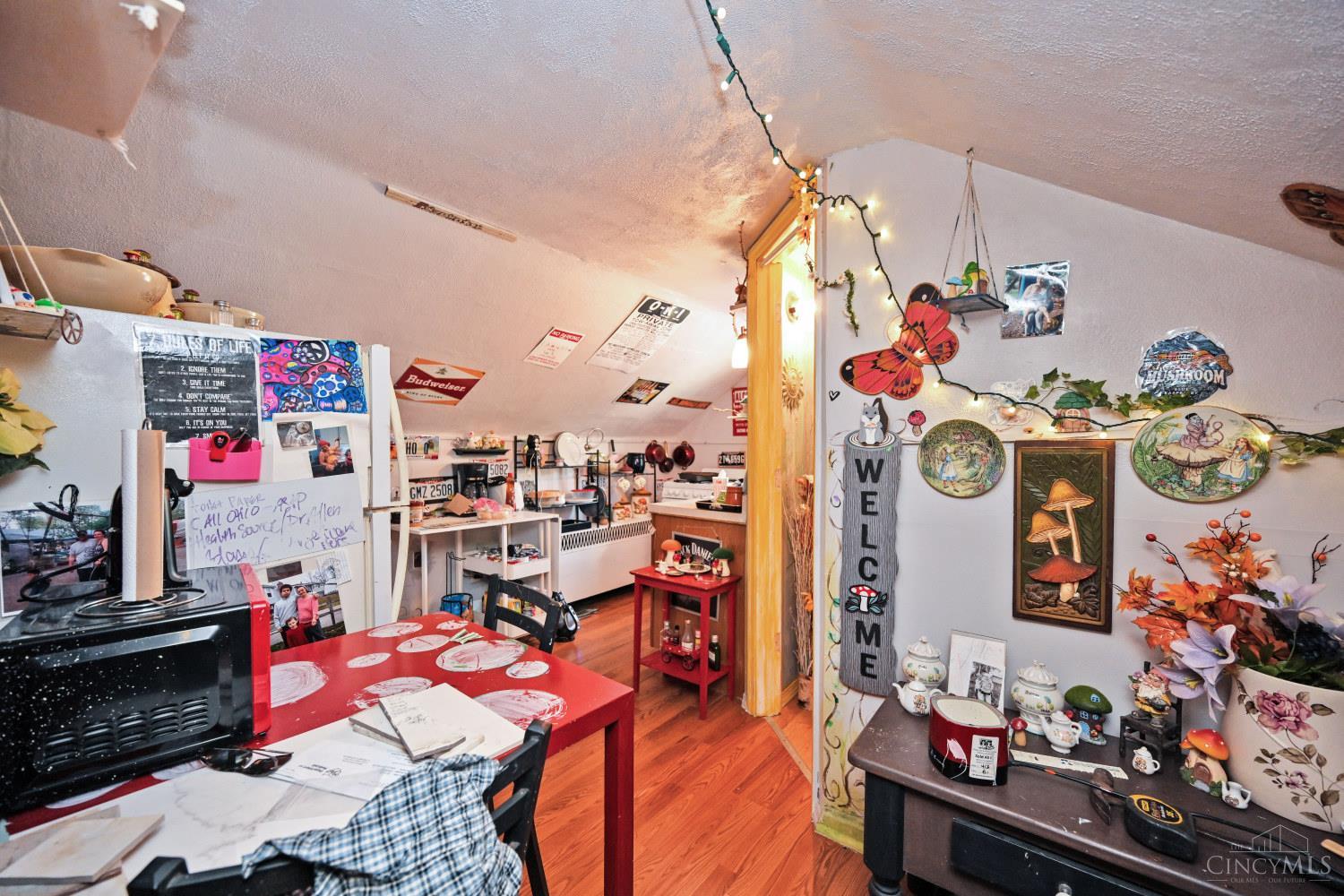 Eclectic kitchen and dining area with red tables, sloped ceilings, and colorful decorations.