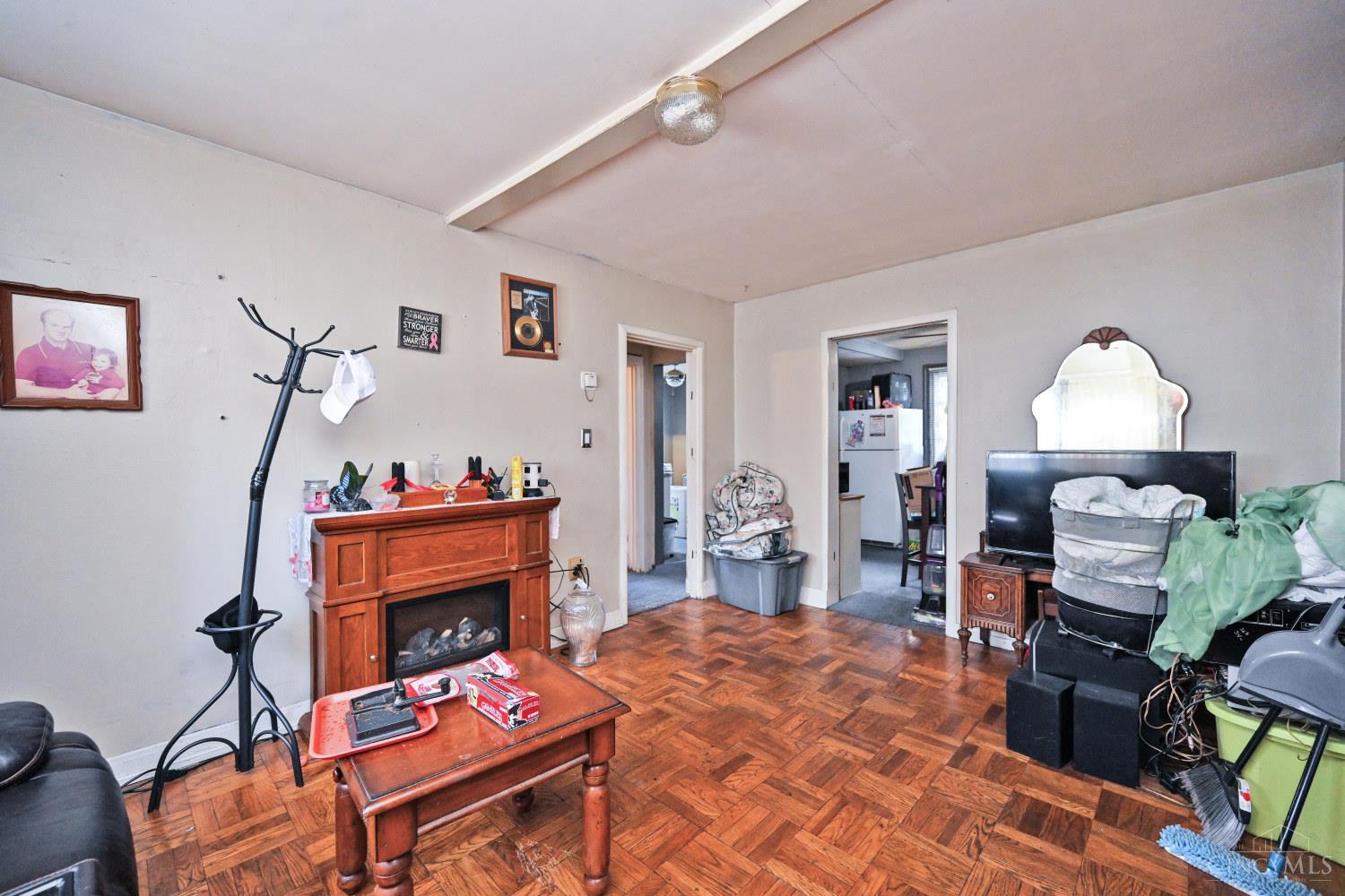 Living room with parquet floors, a wooden fireplace mantel, and a television.