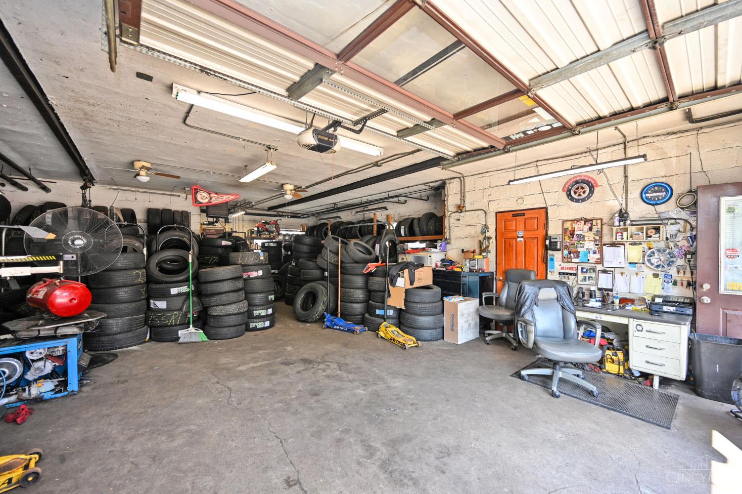 Garage workshop packed with tire stacks, with an overhead door and work area.